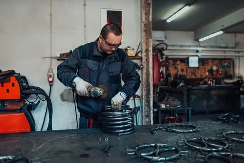 Locksmith in special clothes and goggles works in production. Metal processing Stock-Fotos