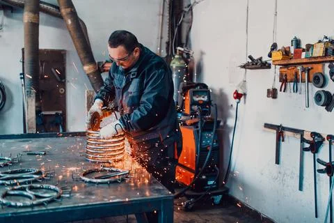 Locksmith in special clothes and goggles works in production. Metal processing Foto stock