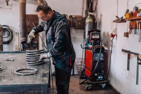 Locksmith in special clothes and goggles works in production. Metal processing Stock Photos