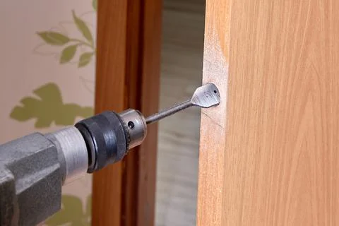 Locksmith use flat bit to wood when drilling hole for latch. Stock Photos