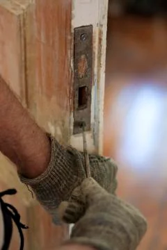 Locksmith use old screwdriver fix the lock on old wooden door Stock Photos
