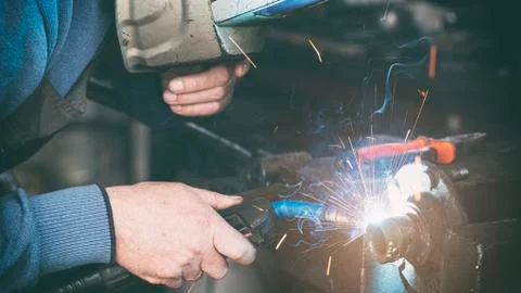 Locksmith welder welds a workpiece in a workshop. Stock Photos