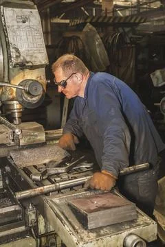 Locksmith working on a drilling machine in a factory Stock Photos