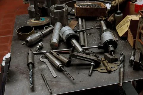 Locksmith workplace mess. Drills and bits for cutting threads on the table. Stock Photos