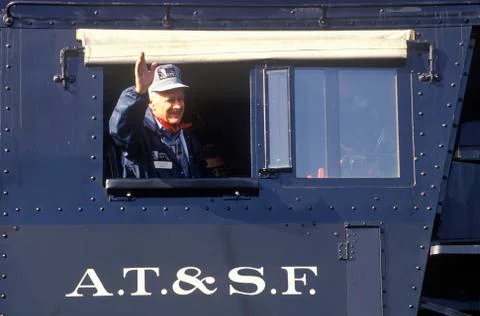 A locomotive engineer waves from the window of an engine of the Atchison, Foto stock