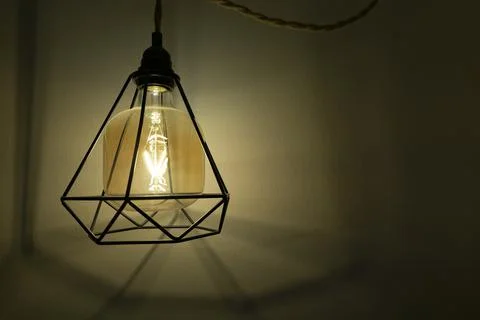 Loft style lamp hanging on a string on a wall in a room. Lighting effect of a Stock Photos