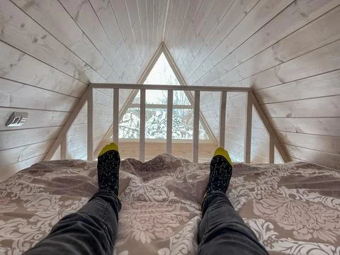 Loft view in A frame cabin, Belarus, socked feet toward frosted window Foto stock