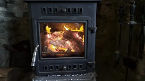 A log burning stove with a fire lit inside glowing and roaring with flames Stock-Footage 265147582