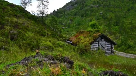 Log cabin sits on a hillside surrounded by grass and trees in Norway during.. Stock Footage 340214010