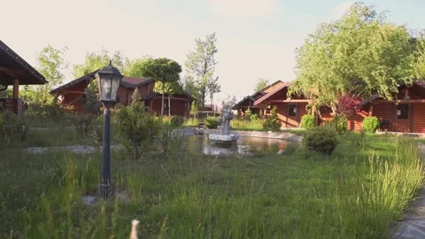 Log cottages on the background of trees and flowering shrubs outside the city Stock Footage 130640392