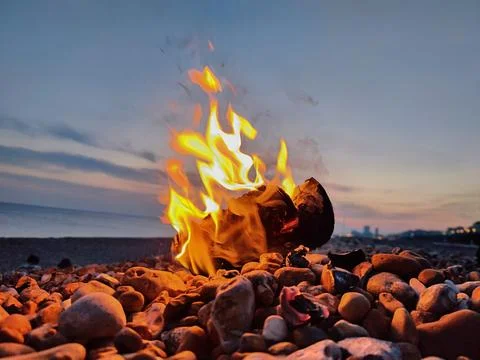 Log fire flames on a pebble beach Stock Photos