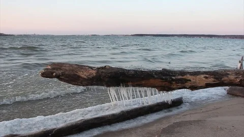 Log with icicles at the freezing river in autumn, Ob reservoir,  Russia Stock Footage 83300357