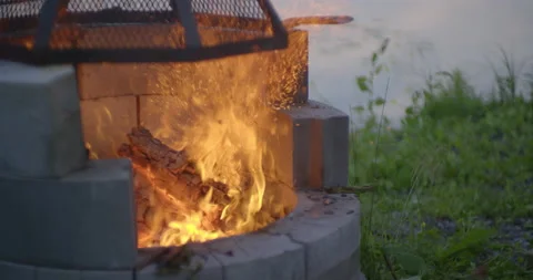 Log piece exploding in fire sparkles in the campfire pit in slow motion Stock Footage 130927576