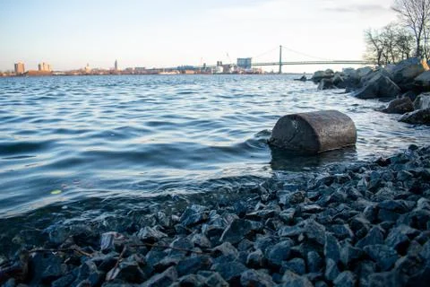 A Log On the Shore of the Deleware River With the Ben Franklin Bridge Behind  Stock Photos
