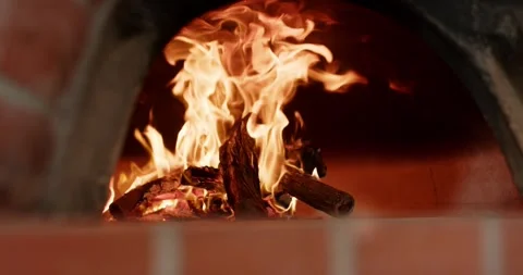 Log stack is burning after ignition, flames are rising, curling in brick oven to Stock Footage 347444795