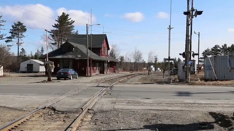 Log truck passes the defunct train station in Jackman, Maine - with audio Stock Footage 81413444