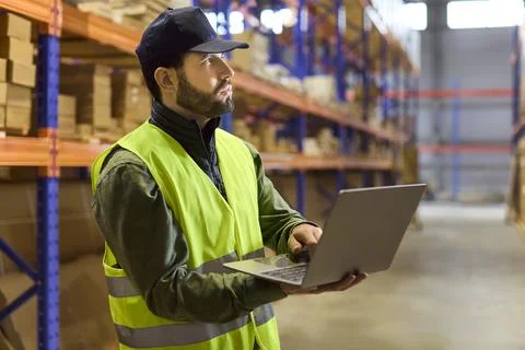 Logistics associate using laptop for inventory audit on warehouse shelves stock Fotos Stock