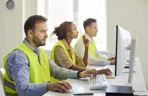 Logistics dispatchers at desktop computers tracking operations in modern office Stock Photos