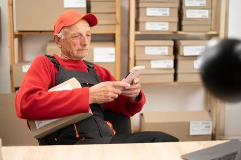 Logistics postal worker checking parcel delivery on smartphone Stock Photos