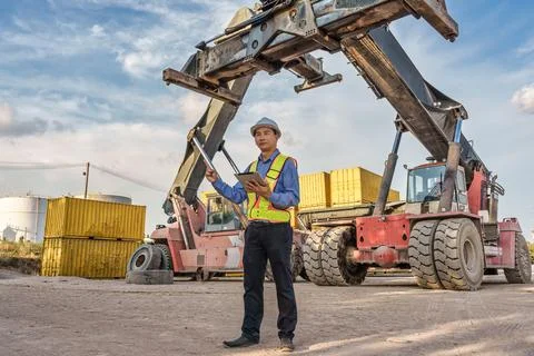 Logistics Supervisor Using Tablet while Presenting Heavy Reach Stacker at C.. Fotos de archivo