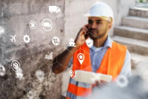 Logistics worker uses technology on site while coordinating transportation and Stock Photos