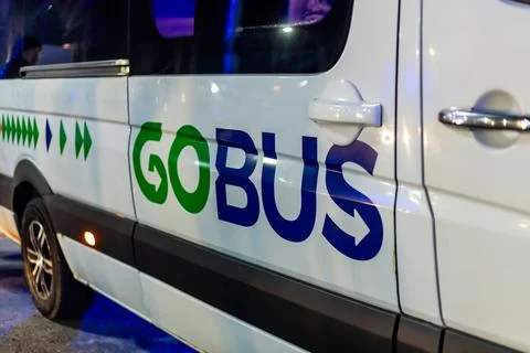 Logo GoBus on side of shuttle bus in Manas airport at night Фото