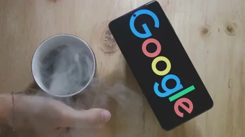Logo of Google on an Android smartphone with hot cup of coffee. Stock Footage 157274493