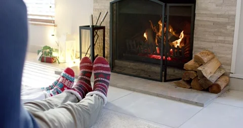 Logs are burning and flickering while couple is sitting with feet by fireplace Stock Footage 345070687