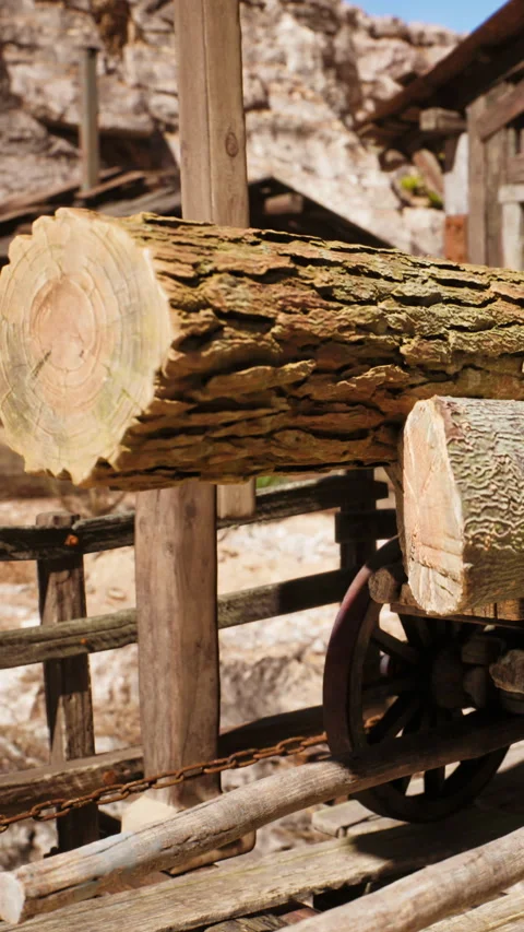 Logs placed on wooden structure near a rustic building in an outdoor setting Stock Footage 342163205