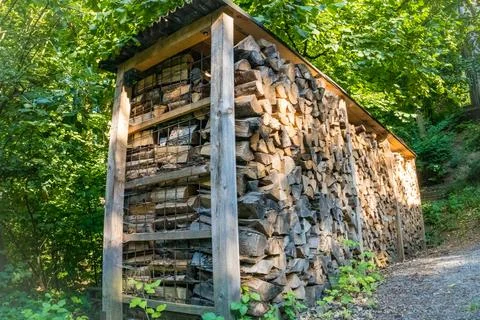 Logs of split firewood stacked in piles are prepared for winter in the village. Stock Photos