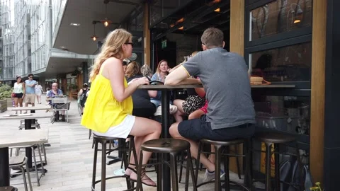 London bar Battersea summer 2020 couple on bar stools waiter brings drinks Stock Footage