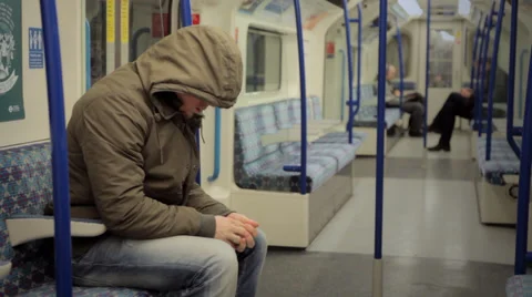 LONDON:  Man with a hoodie sits down in a tube train Stock Footage