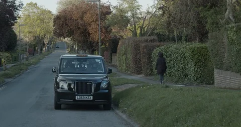 London / United Kingdom (UK) - 04 19 2020:  Woman walking by black taxi cab. Stock Footage