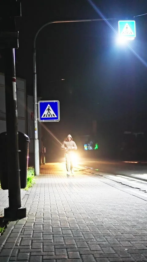A lone athlete runs down a dimly lit street decorated with brightly lit signs at Stock-Footage 307125296