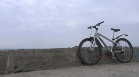 A lone bicycle stands on old high concrete pier during huge storm. Stock Footage 68321764
