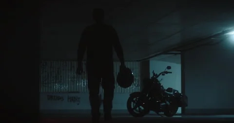 Lone Biker Approaching Motorcycle in Dark Underground Parking Stock Footage 307512074
