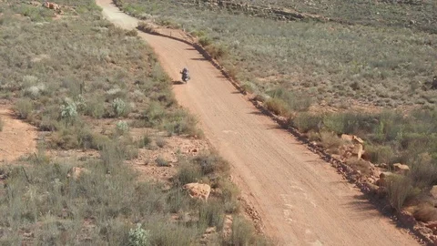 Lone biker Riding Down Desolated Dirt Road in the desert. Stock Footage 106038160