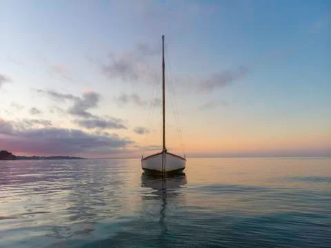 Lone boat moored during magic hour gently bobs on the water - DJI 0059 Stock Photos