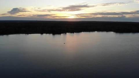 Lone Boat Over Still Lake at Sunset Stock Footage 129771353