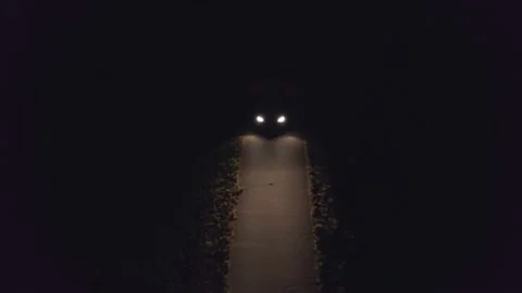 A lone car drives a small road at night with its lights on. Lost in the dark, Stock Footage 171827271