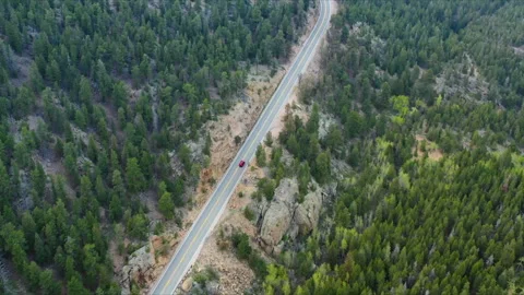 A lone car travels on an empty road through the Colorado mountains Stock Footage 247363875