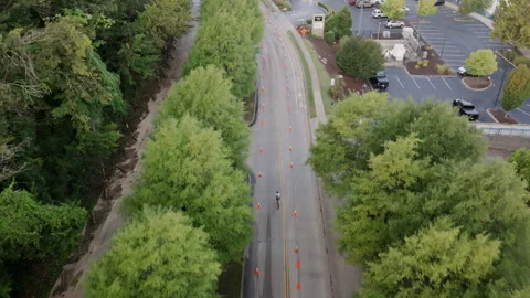 A lone cyclist powers through a tree-lined stretch of the Ironman Chattanooga Stock Footage 320066075