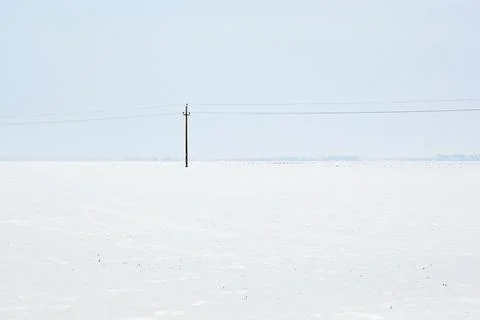 A Lone Electric Pole in Empty Winter Landscape with Snow Foto stock