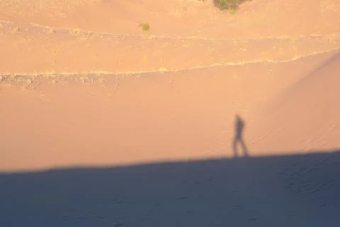 Lone explorer on the desert, casting shadow on the sand dunes on a hot sunny day Stock Photos