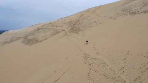 Lone explorer walking along huge sand dunes at Dune of Pilat Stock Footage 102509530