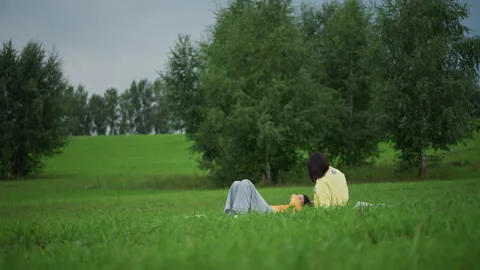 Lone female gazes over open fields thoughtfully, An isolated woman resting in Stock Footage 325332907