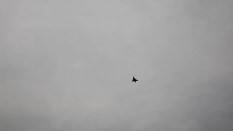 Lone fighter jet cuts through overcast sky in dramatic solo maneuver evoking ste Stock Footage 311662226