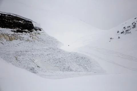 A lone figure challenges the aftermath of an avalanche, skiing through the .. Stock Photos