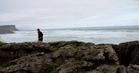 A lone figure finds solace in the rhythmic dance of the sea, Stock Footage 333207993