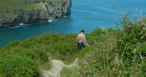 A lone figure navigates a rugged coastal path, 库存影片 343672385